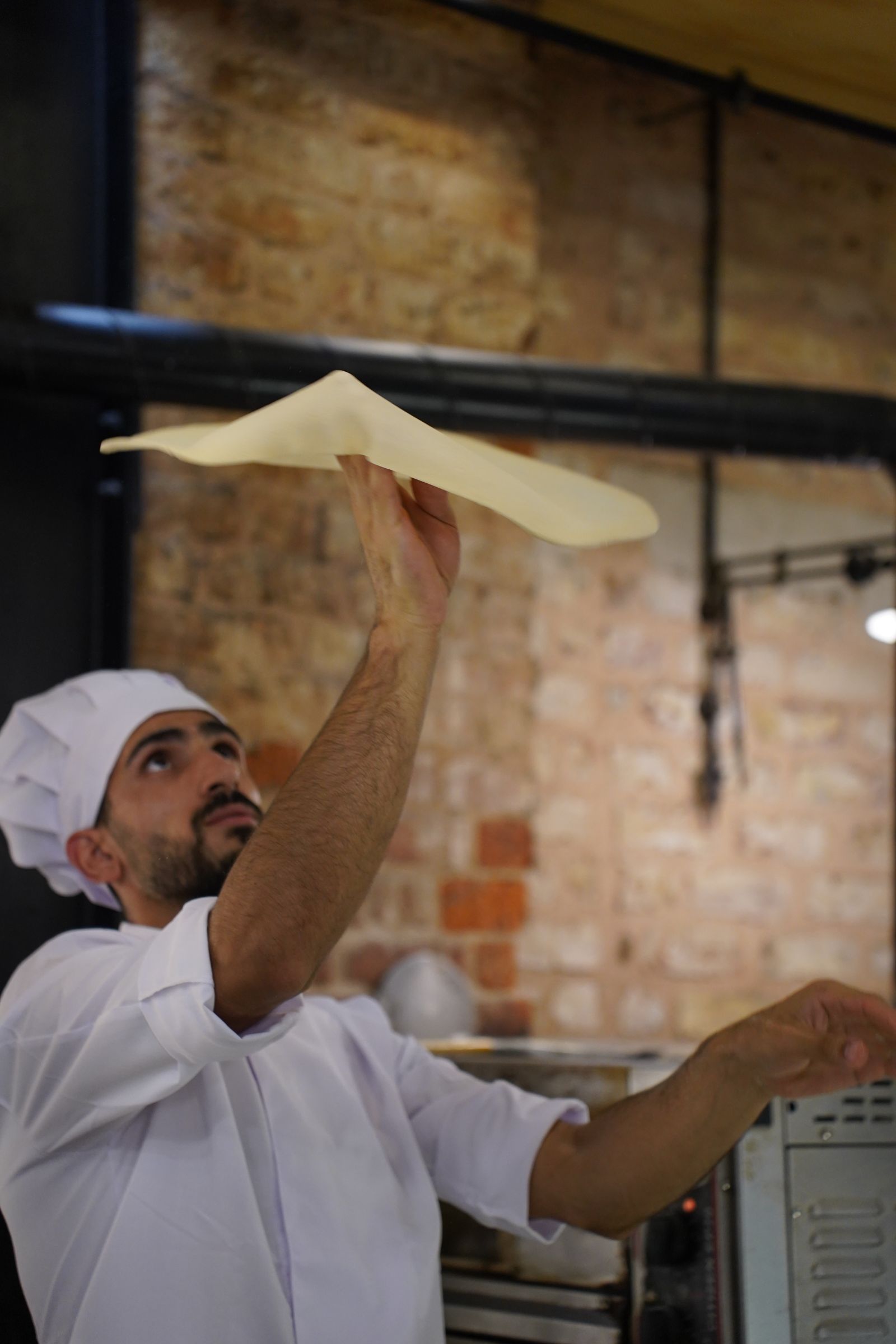 Pizzaiolo bei der Arbeit am Holzofen — Symbolbild
